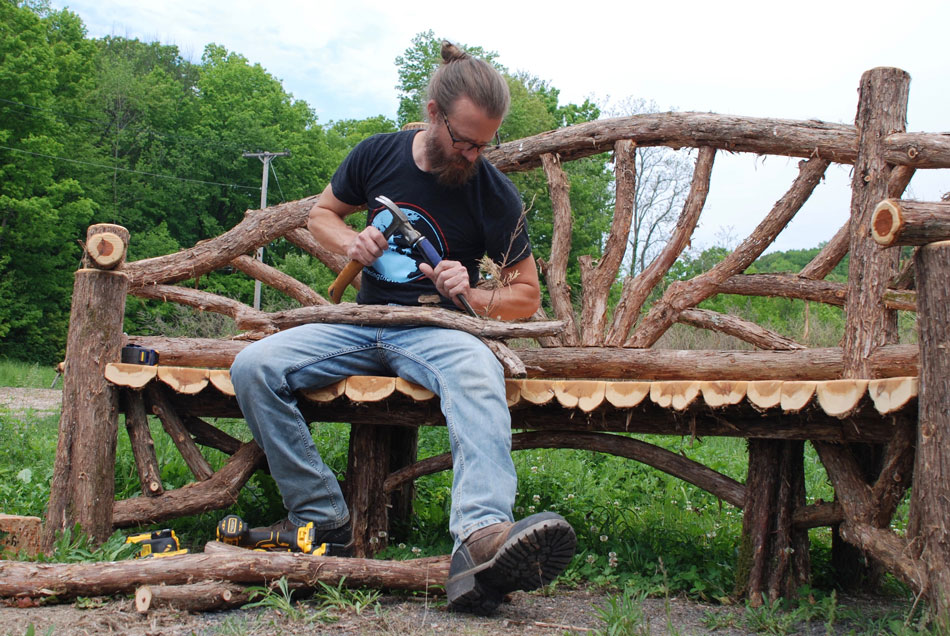 Outdoor rustic garden bench built using bark-on trees and branches titled the Dutchess News Poet's Bench
