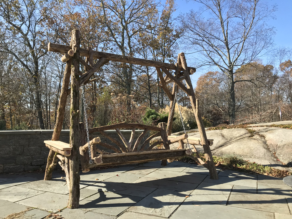 Outdoor rustic bench swing built using bark-on trees and branches titled the Bethany Bench Swing