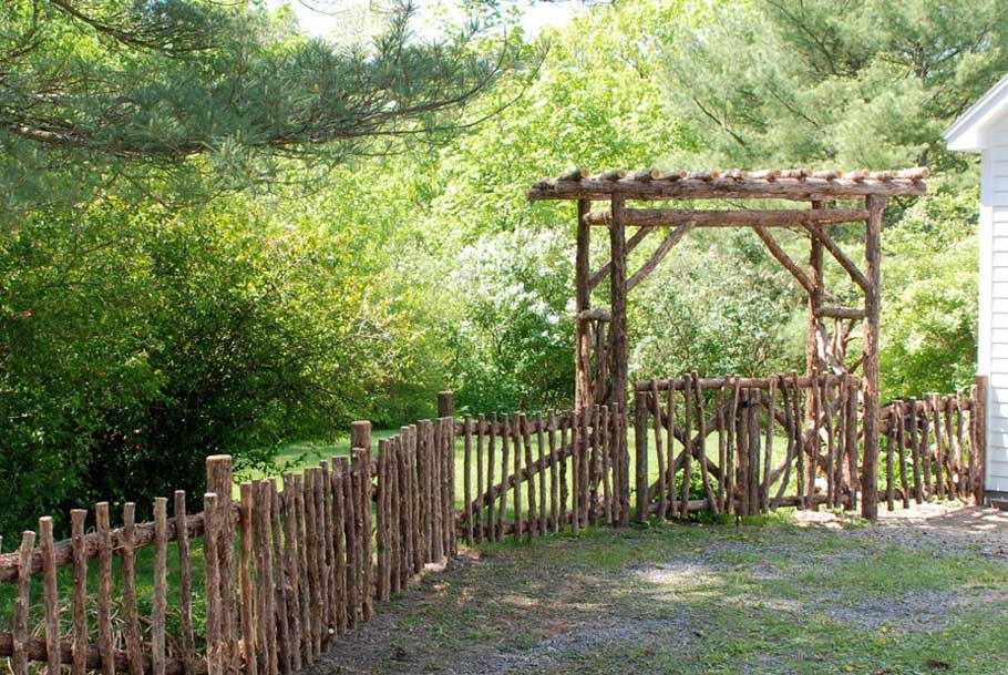 Rustic natural arbor and fencing made from bark-on cedar logs, twigs, and branches titled the
