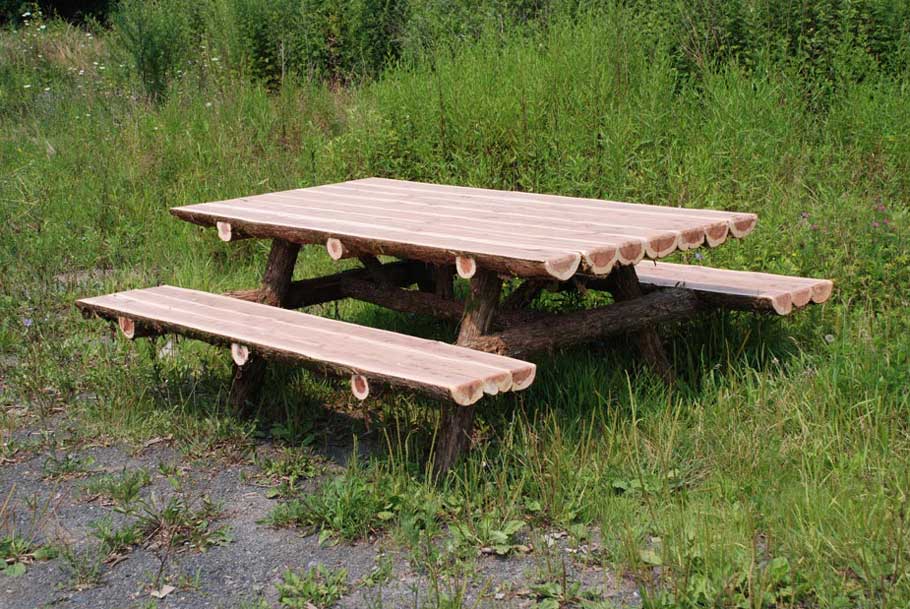 Outdoor rustic picnic table built using natural cedar logs titled the Half-Round Picnic Table