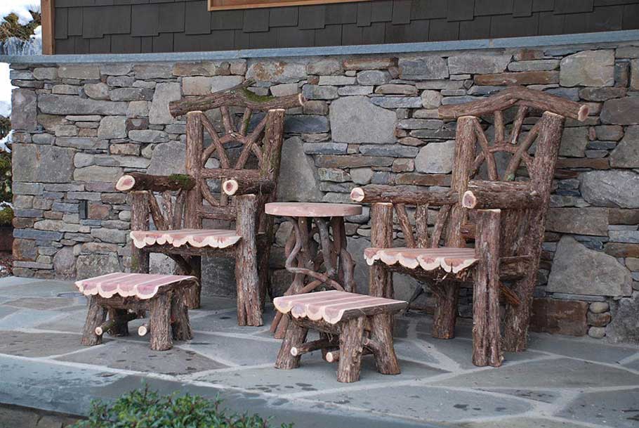 Outdoor rustic patio chairs, ottomans, and table built using bark-on trees and branches titled the Windham Set