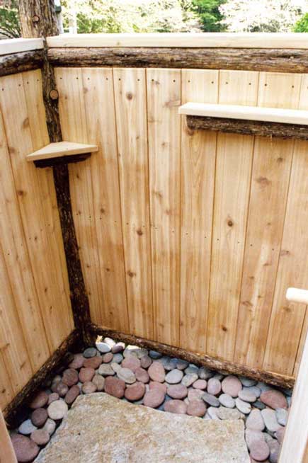 A one of a kind outdoor shower constructed with bark-on cedar trees and cedar deck boards