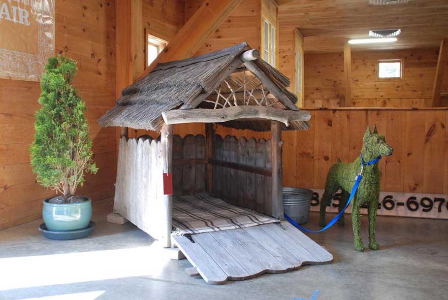 Custom doghouse built with cedar trees, boards, and thatch titled the Sugar Shack