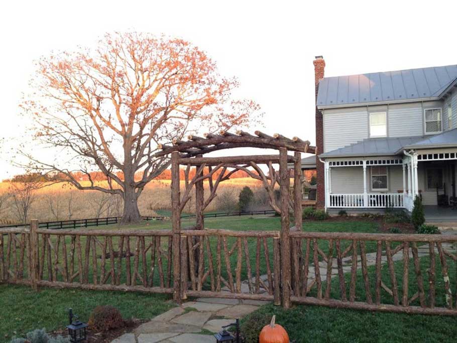 Rustic arbor and fencing custom built using cedar trees and branches titled Plunkett Arbor & Fencing
