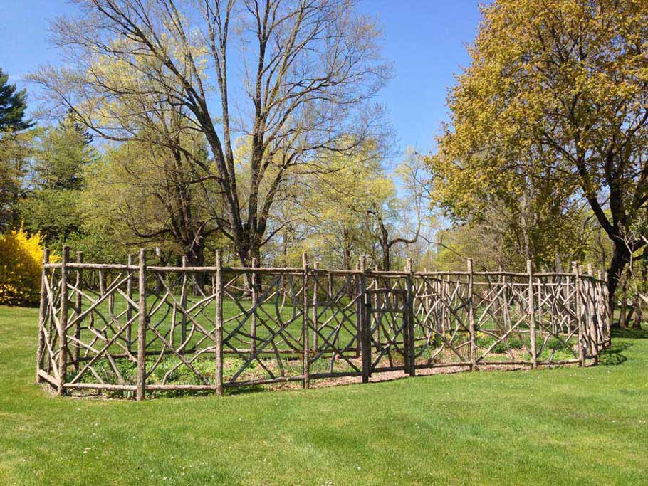 Rustic garden fencing built using bark-on trees and branches titled Squire Fencing