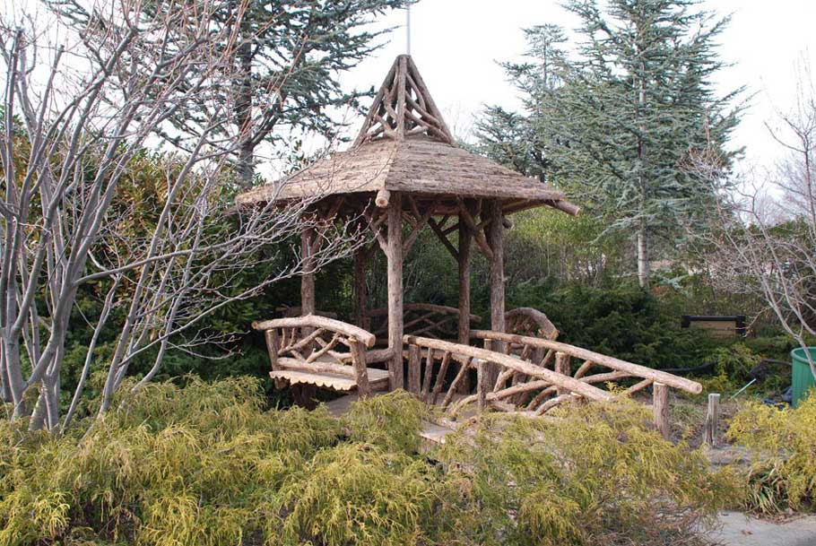 Gazebo and bridge built in the rustic style using logs and branches installed at Hofstra University
