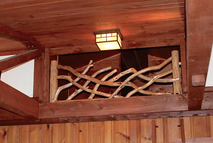 A loft railing constructed using stripped eastern red cedar trees and branches