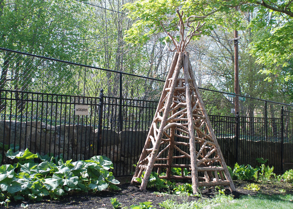 Outdoor rustic tepee built using bark-on trees and branches at the Easton Children's Museum