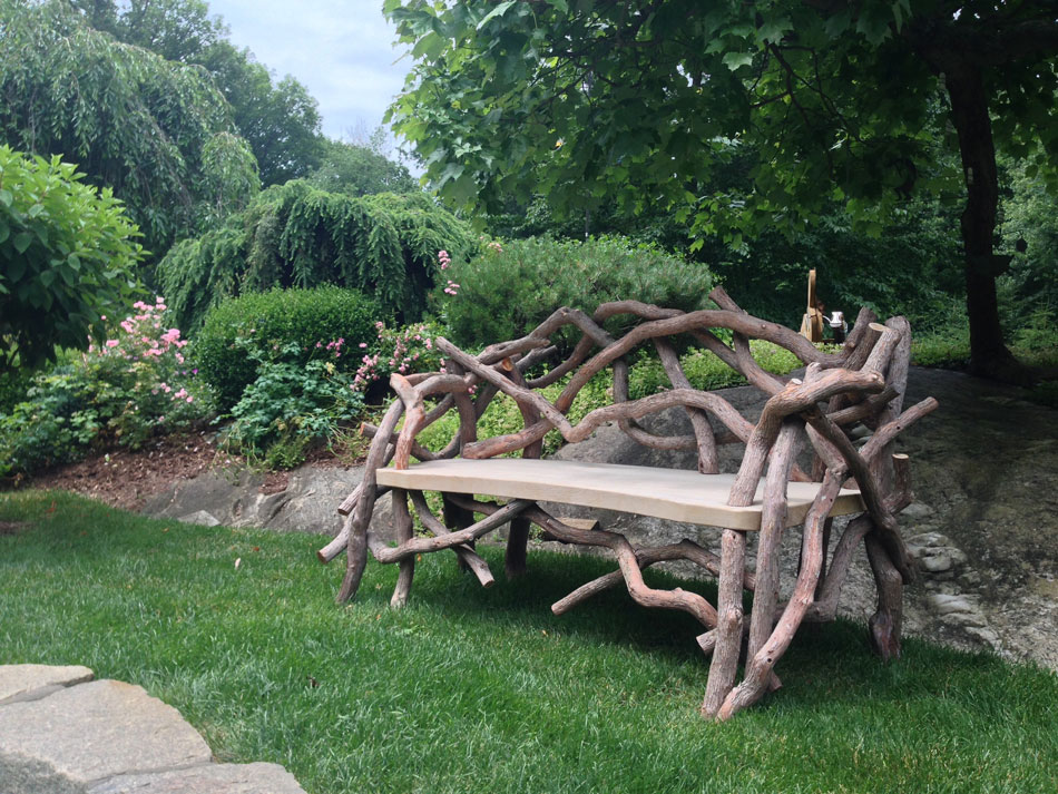 Outdoor rustic garden bench built using bark-on trees and branches titled the Benson