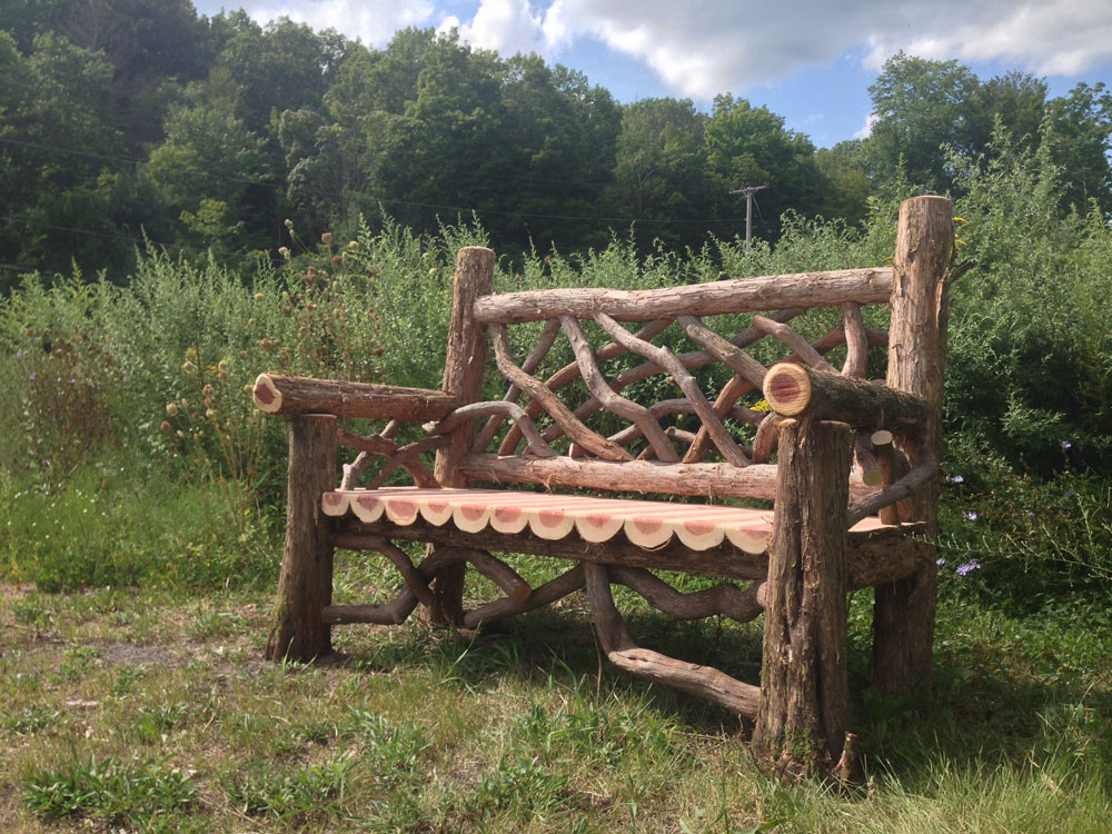 Outdoor rustic garden bench built using bark-on trees and branches titled the Putnam