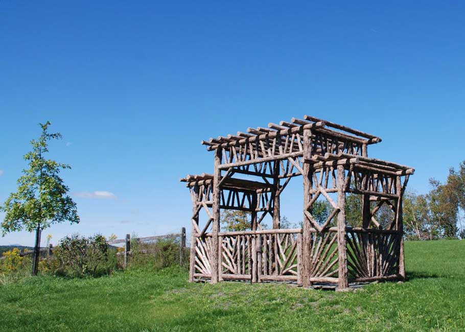 Outdoor rustic entrance pavilion built using bark-on trees and branches titled the Taylor Entrance Structure
