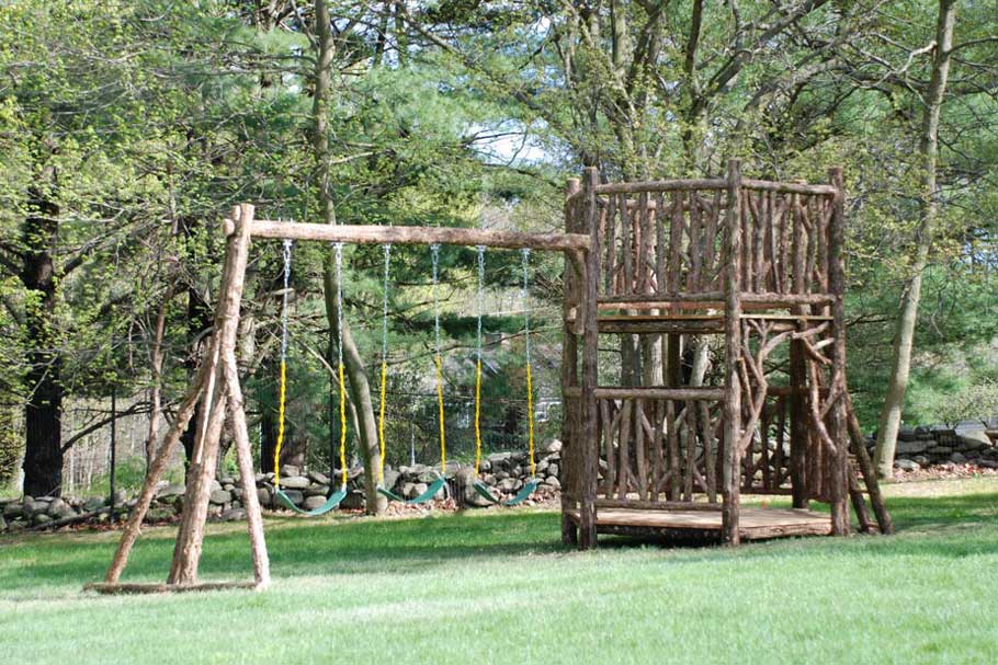 Outdoor rustic playhouse and swing set built using bark-on trees and branches titled the Hudson Playhouse