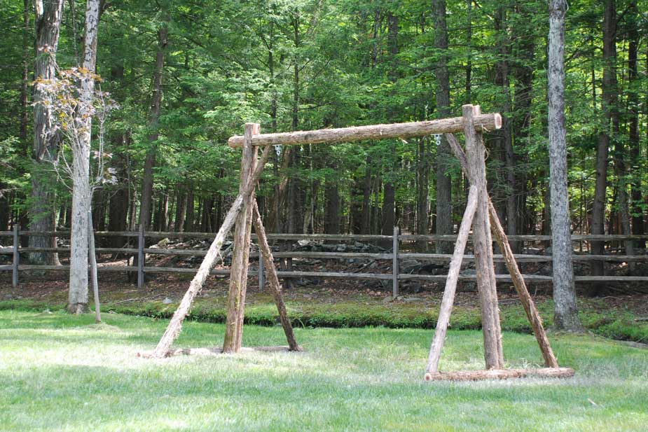 Natural wood swing frame built with trees and branches titled the Stand Alone Swing Frame